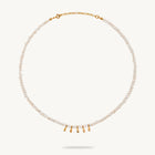 A delicate pearl necklace with a gold chain extender and five small gold teardrop charms at the center, displayed on a clean off-white background.