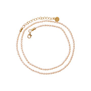 A delicate pearl necklace with gold-plated chain, a lobster clasp, and a small round gold brand tag, displayed on a clean white background.