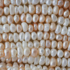 A close-up, top-down view of numerous irregular baroque pearls in soft cream, ivory, and pale peach tones, filling the entire frame.