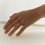 Hand wearing a yellow gold and faceted black diamond ring on a white background