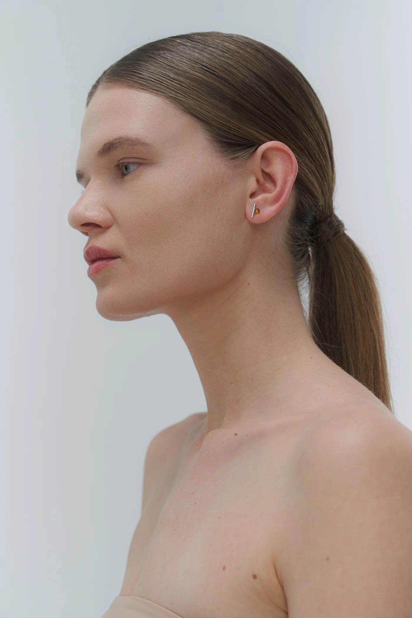 Silver earrings by Adele Notes, featuring a band and small Baltic amber element.