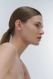 Woman with a ponytail wearing silver & amber earrings against a plain background
