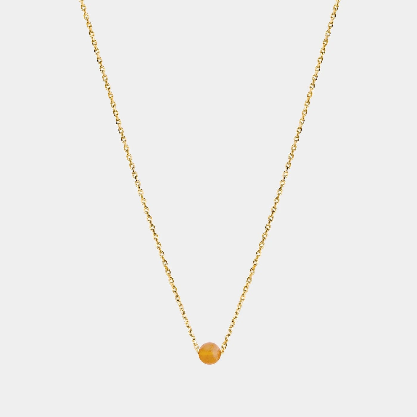 Gold necklace with small Baltic amber pendant by Adele Notes.