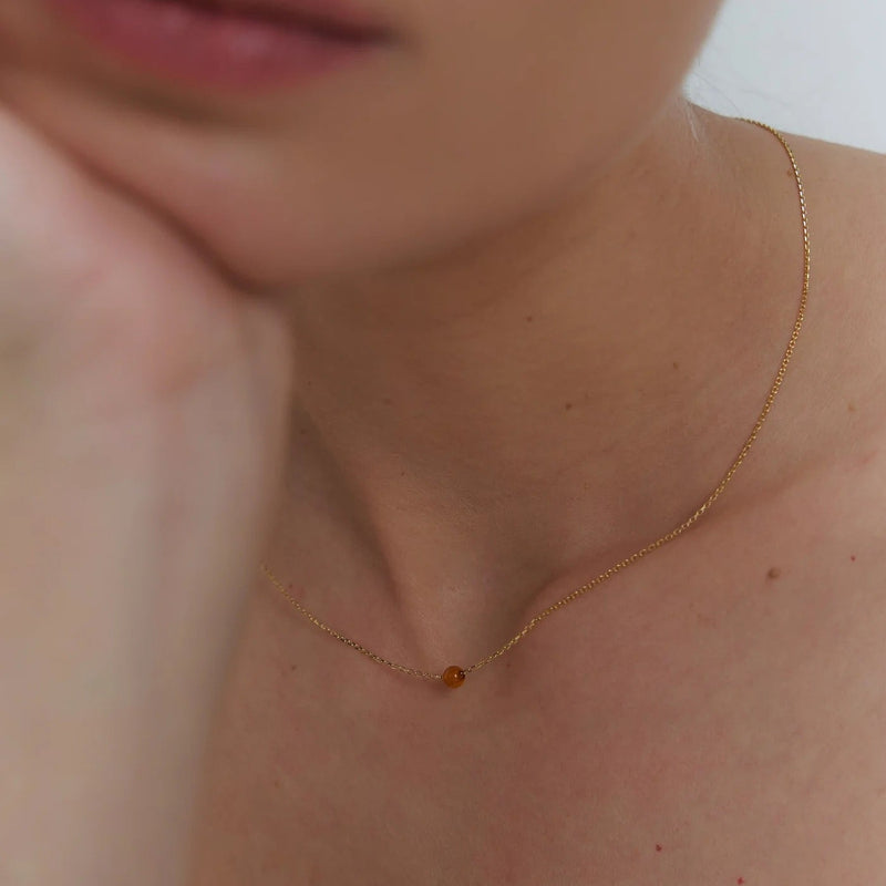 Gold necklace with small Baltic amber pendant by Adele Notes.