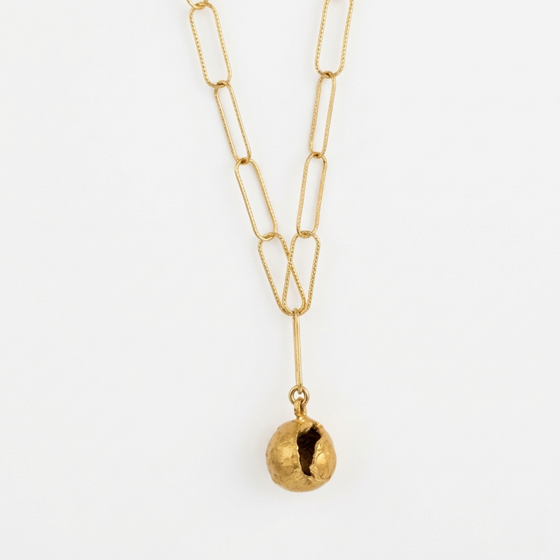 Gold necklace with a unique pendant on a white background
