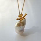 Gold-plated silver bird pendant accompanied by a baroque-shaped freshwater pearl. 