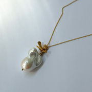 Gold-plated silver bird pendant accompanied by a baroque-shaped freshwater pearl. 