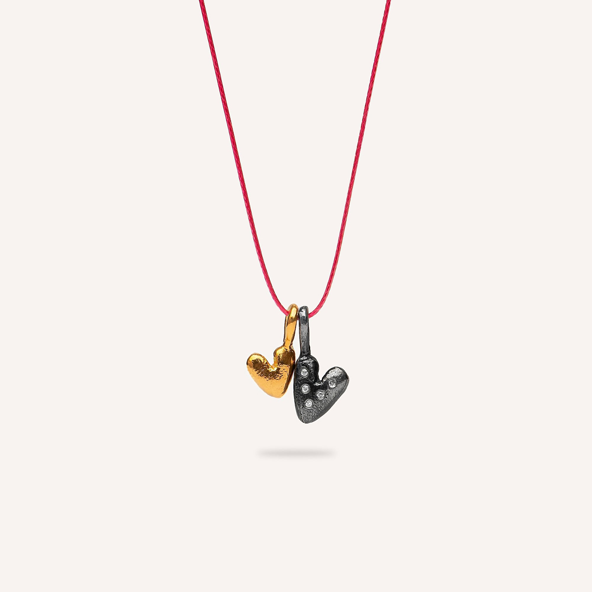 Necklace with heart-shaped pendants on a red cord against a white background