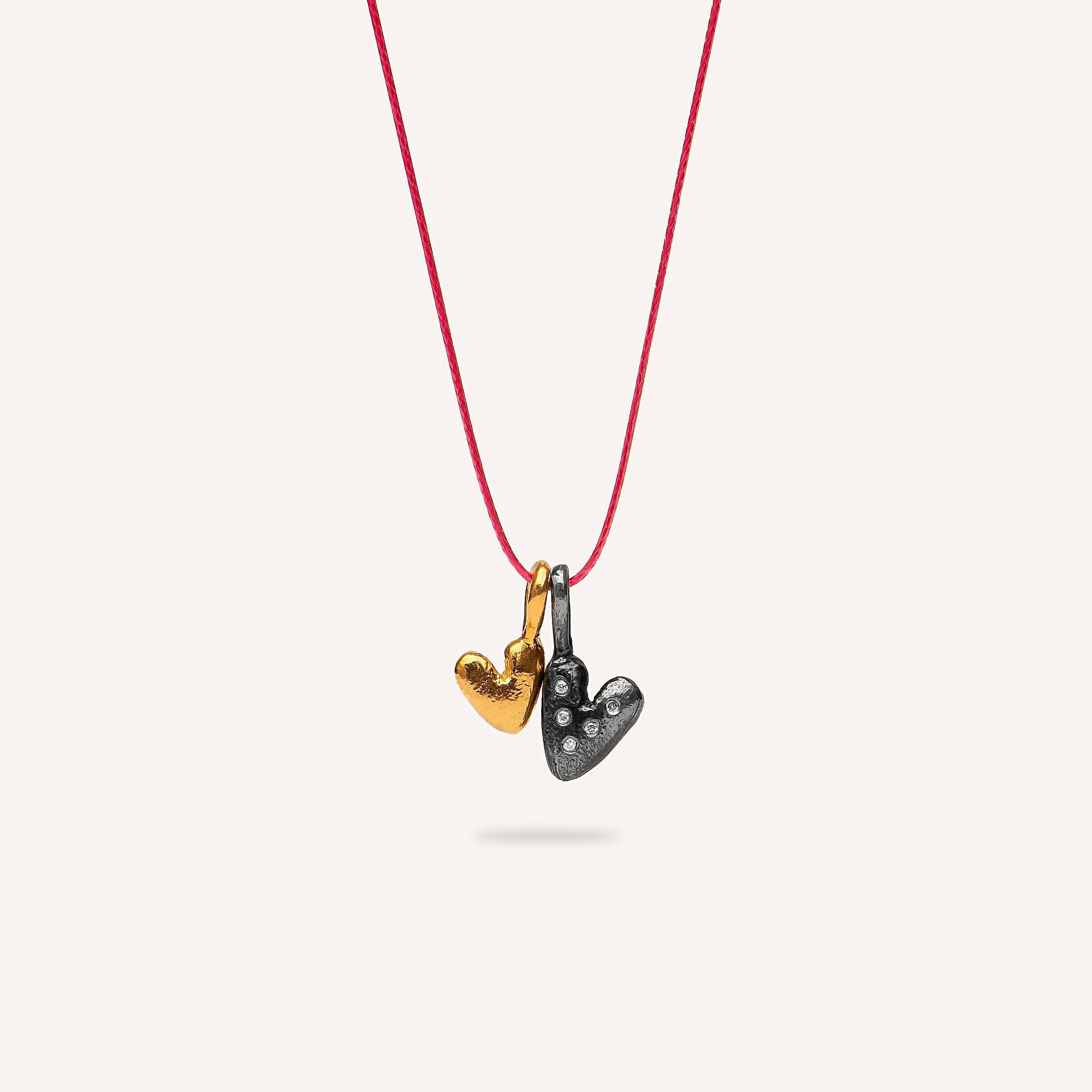 Necklace with heart-shaped pendants on a red cord against a white background
