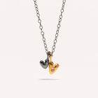 A gold-plated oxidized silver necklace with two heart-shaped silver pendants, one with a pink sapphire center.