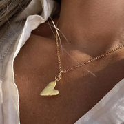 A gold plated silver necklace with a heart-shaped pendant, displayed on a person wearing a light-colored shirt.
