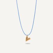 A gold plated silver necklace with a heart-shaped pendant on a blue string.