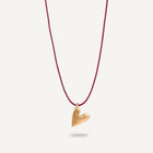A gold plated silver necklace with a heart-shaped pendant on a burgundy string.