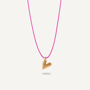 A gold plated silver necklace with a heart-shaped pendant on a pink string.