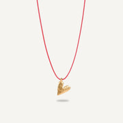 A gold plated silver necklace with a heart-shaped pendant on a red string.