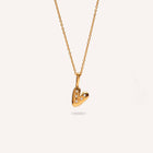 Gold heart-shaped pendant necklace on a light gray background