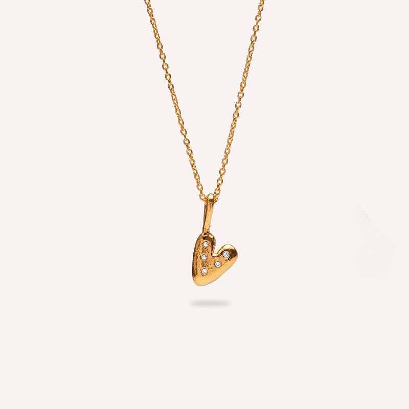 Gold heart-shaped pendant necklace on a light gray background