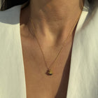 Gold-plated silver pendant with dark pearl by Near Me on a persons neck.