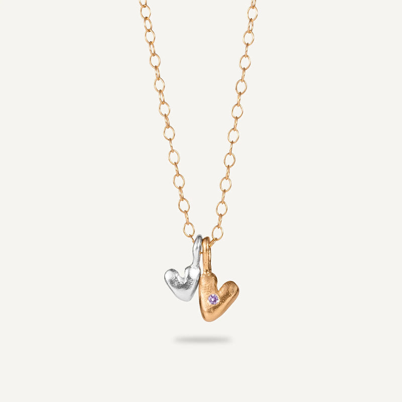 A gold-plated silver necklace with a heart-shaped pendant featuring a sapphire center.