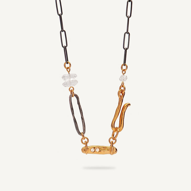 Necklace with gold and black chain and decorative elements on a white background