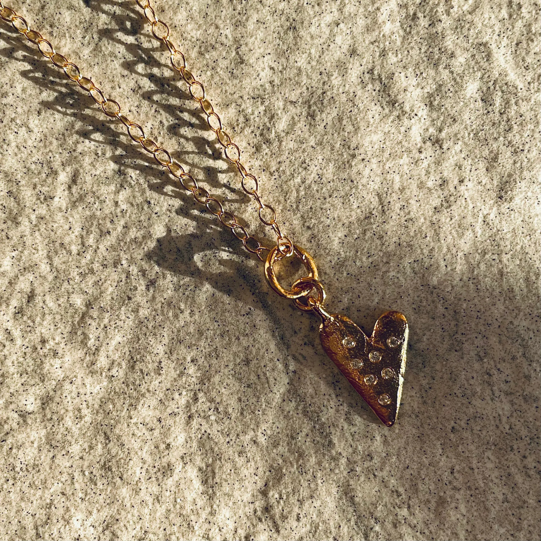 A gold plated silver necklace featuring a heart-shaped pendant with sapphires.