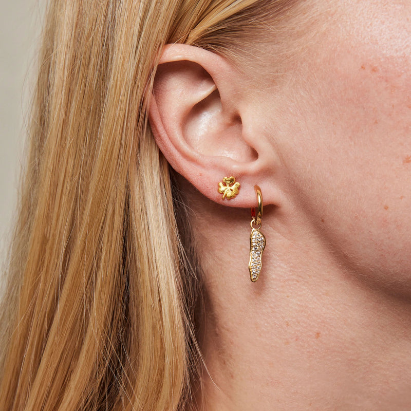 Close-up of a person wearing gold earrings with a neutral background