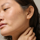 Close-up of a woman wearing a gold earring with a neutral background