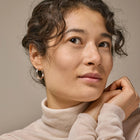 Woman wearing a beige turtleneck sweater against a neutral background