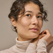 Woman wearing a beige turtleneck sweater against a neutral background