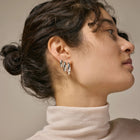 Close-up of a woman wearing silver hoop earrings with a neutral background