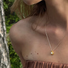 Close-up of a person wearing a gold-plated silver necklace with Akoya pearl