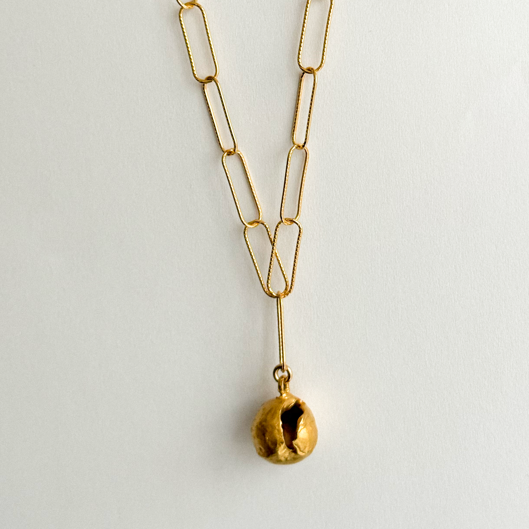 Gold necklace with a unique pendant on a light gray background