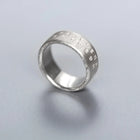 Silver ring with engraved text on a light gray background