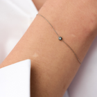 Hand wearing a white gold bracelet featuring a small pendant set with round brilliant-cut diamond.