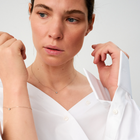 Woman wearing a white gold bracelet featuring a small pendant set with round brilliant-cut diamond.