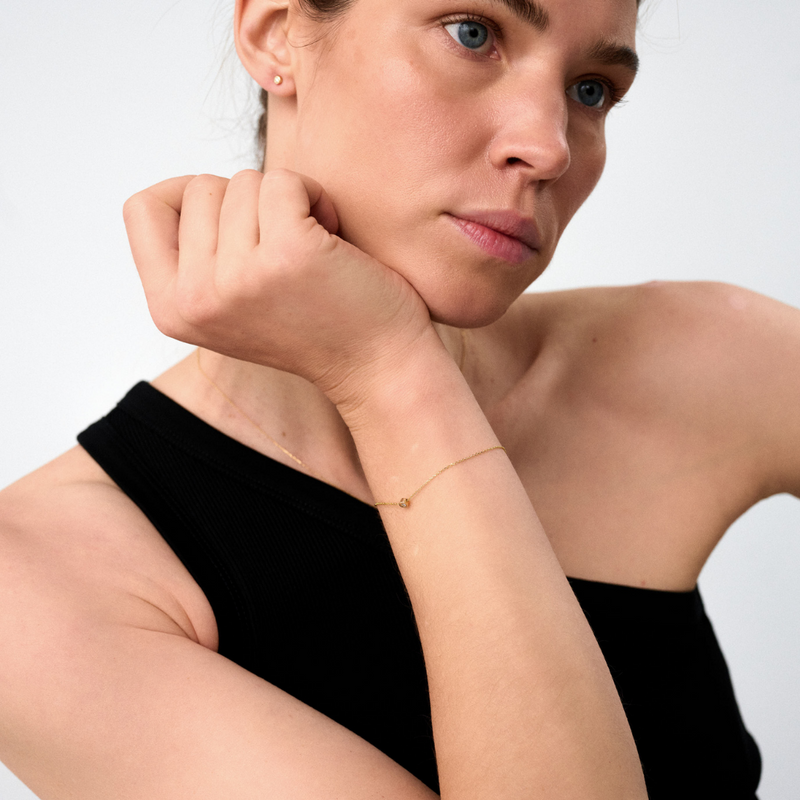 Woman wearing a white gold bracelet featuring a small pendant set with round brilliant-cut diamond.
