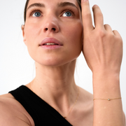 Woman wearing a yellow gold bracelet featuring a small pendant set with round brilliant-cut diamond.