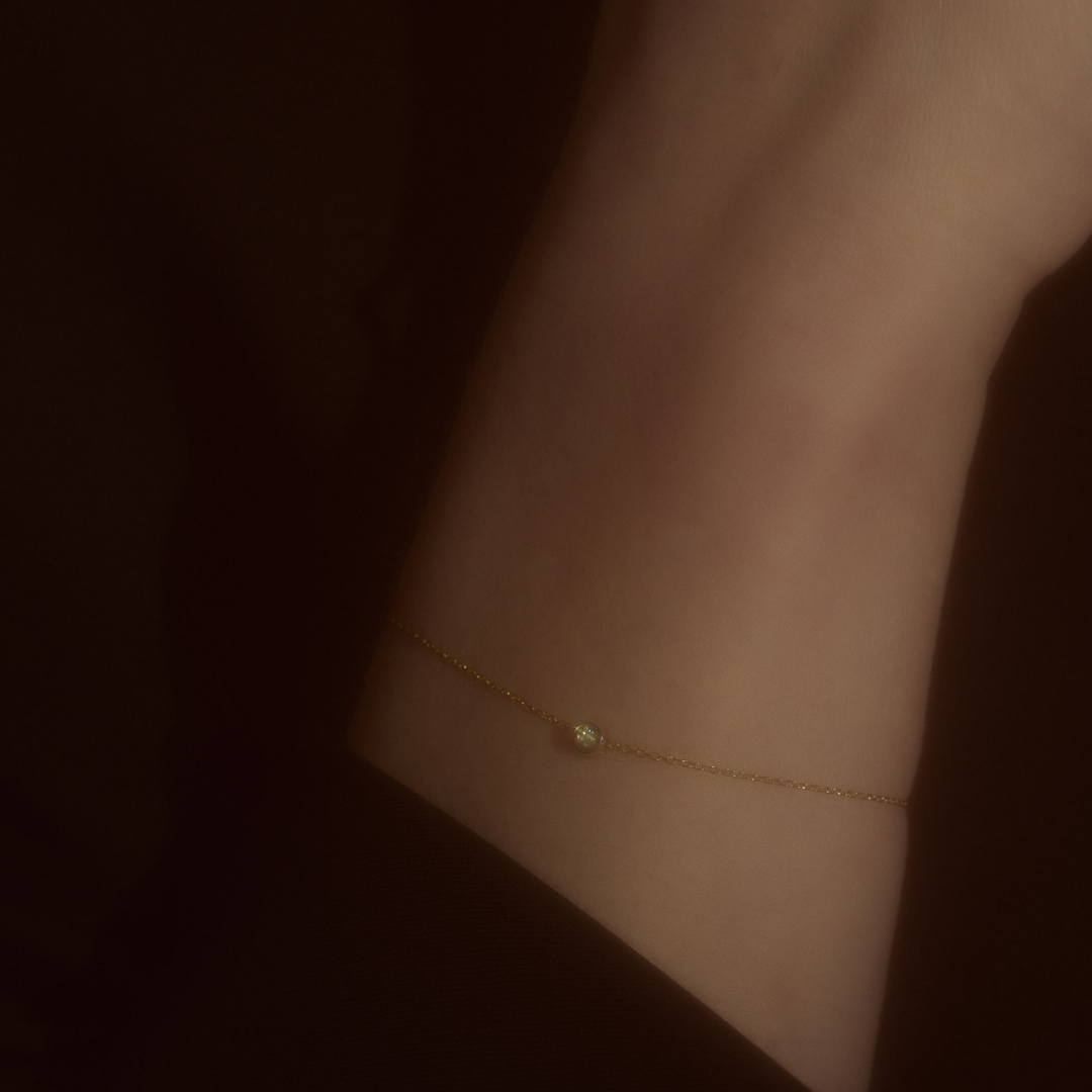 Hand wearing a white gold bracelet featuring a small pendant set with round brilliant-cut diamond.