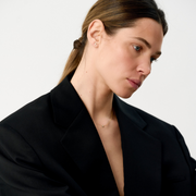 Woman wearring yellow gold pendant and earrings featuring a round brilliant-cut diamonds.