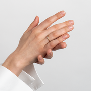 Close-up of a hand wearing a diamond ring on a light gray background