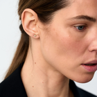 Close-up of a woman wearing a small gold & diamonds stud earring with a plain background