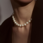 Woman wearing a necklace composed of round freshwater pearls and fine sterling silver.