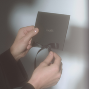 A person holding a black gift card with the brand name 'miutto' written on it, tied with a black ribbon.