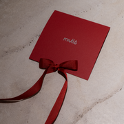 Red card with a bow on a textured surface, featuring the brand 'miutto'.