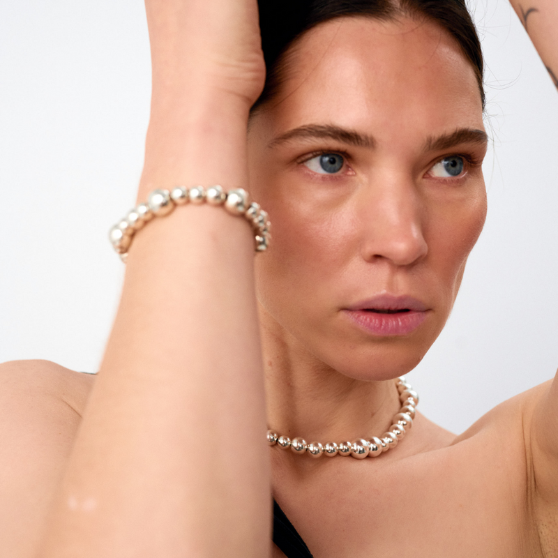Woman wearing statement bracelet crafted from fine sterling silver beads in varying sizes. 