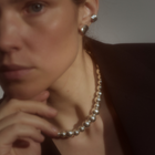 Woman wearing a statement necklace crafted from fine sterling silver beads in varying sizes. 