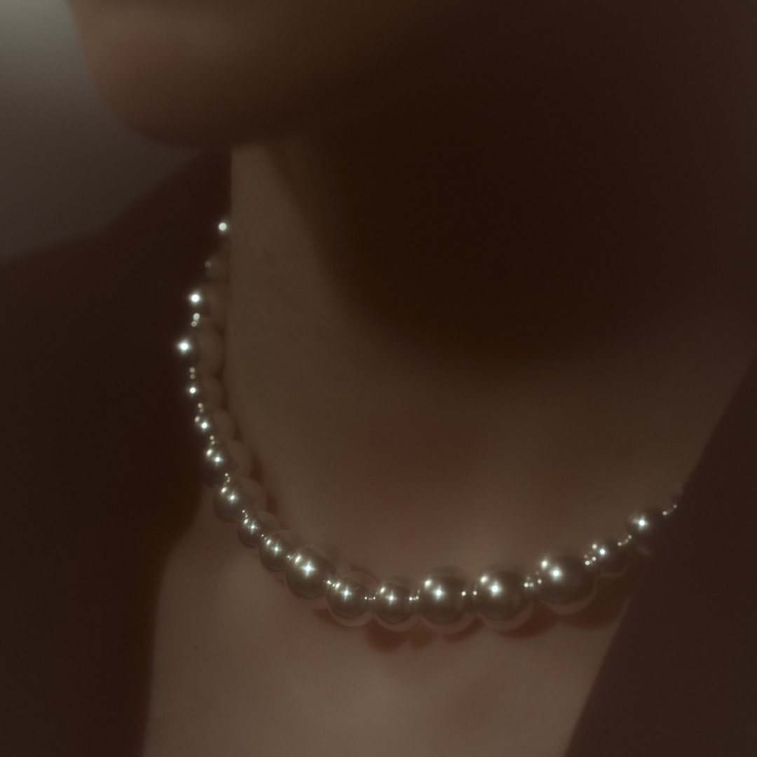 Woman wearing a statement necklace crafted from fine sterling silver beads in varying sizes. 
