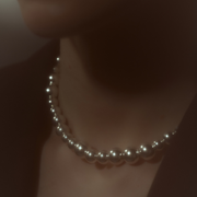 Woman wearing a statement necklace crafted from fine sterling silver beads in varying sizes. 