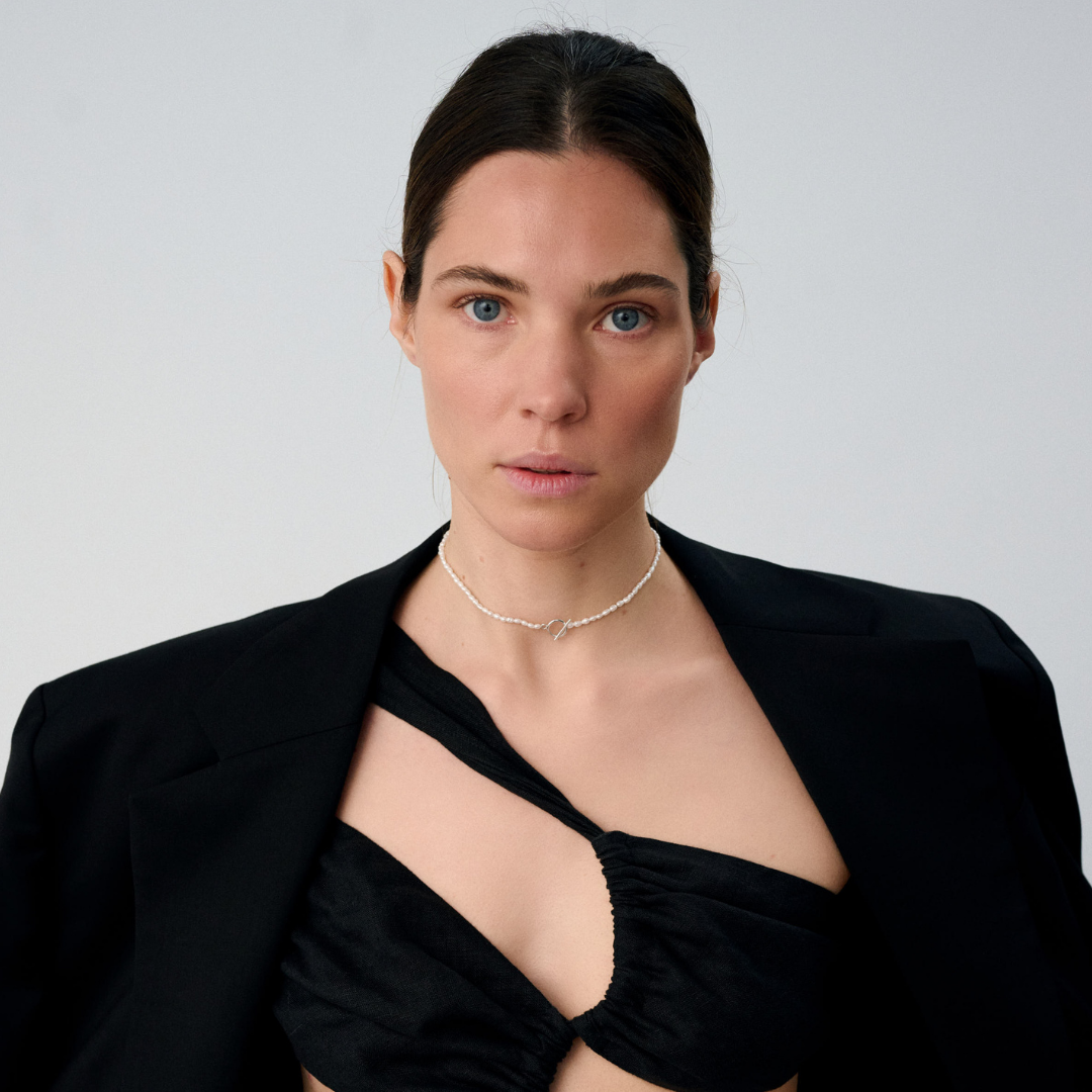 Woman wearing a delicate freshwater pearl necklace featuring organically shaped pearls and a minimalist silver clasp.