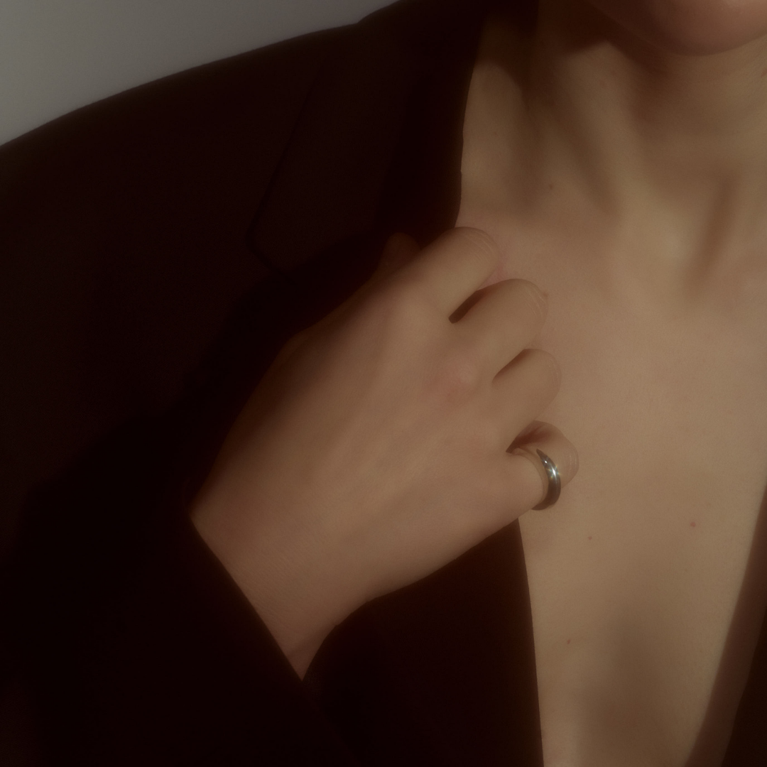 Woman wearing a minimalist polished silver ring with a smooth, rounded silhouette.